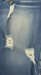 Authentic distressed denim fabric with frayed rips, perfect for fashion projects and grunge aesthetics.