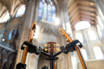 Close-up of three guitars in there stands within a British cathedral prior to a rock and pop concert. The fine cathedral architecture can be seen in the background.