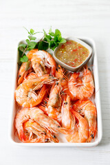 Grilled shrimps with spicy sauce in a white tray.