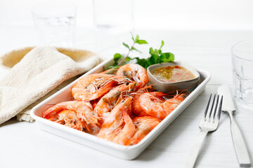 Grilled shrimps with spicy sauce in a white tray.