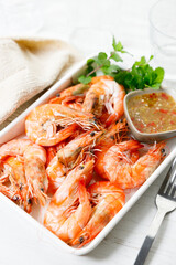 Grilled shrimps with spicy sauce in a white tray.