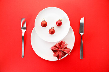 White dishes with Christmas ornaments on red background.