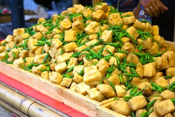 Pile of fried tofu and green chili peppers sold at a traditional food market
