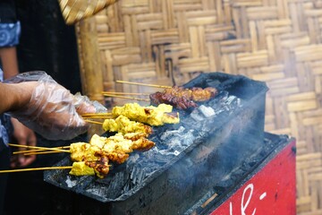 Satay skewers are being grilled on hot charcoal with smoke, authentic Indonesian street food