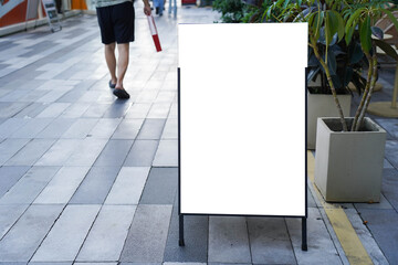 Blank white outdoor advertising stand sandwich board mock up template. Clear street signage board placed by an outdoor dinning area of a restaurant.