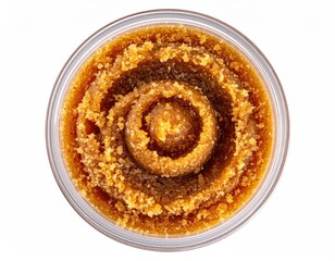 A clear container holds a golden-brown, textured paste with concentric circular patterns, suggesting a handcrafted or artisanal product