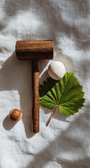Wooden mallet, white stone, leaf, hazelnut on linen