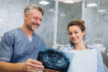 Obraz premium Dentist reviewing X-ray with patient in modern dental clinic during afternoon appointment