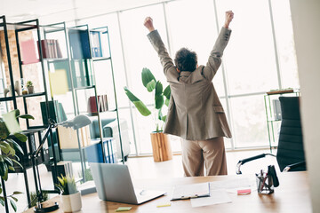 Businesswoman celebrates professional accomplishment in modern workspace with natural light and...