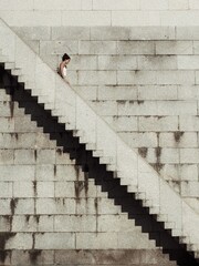 A woman is walking down the stone stair on a sunny day.