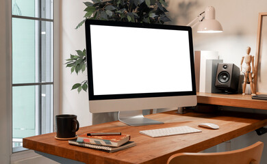 Modern all-in-one desktop computer with a blank screen is placed on a clean wooden desk. The organized workspace features creating a professional and tidy home office or creative studio environment.