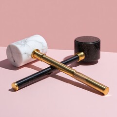 Two crossed decorative mallets, one white marble, one dark stone, with brass accents, on a pink background