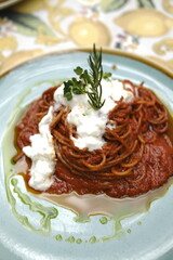 Spaghetti pasta with tomato sauce, cream cheese and rosemary garnish