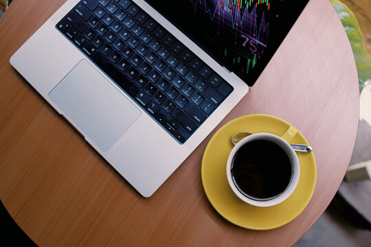 analyzing stock market data on a laptop with financial trading charts and a cup of coffee at home. - Powered by Adobe