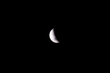 A breathtaking partial lunar eclipse reveals the Moon partially covered by Earth’s shadow, glowing softly against the deep, starless dark sky of a calm night.