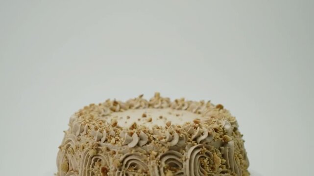 A beautifully decorated cake with nut topping, set against a plain background, ideal for celebrations or events