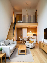 A duplex room in wooden interior with two levels and bedroom upstair, kithcen pantry, dining table downstair.