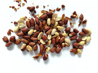 Scattered raw peanuts with skins on a white background, closeup, healthy snack concept.