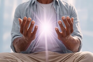 A person with dark skin holds cupped hands, radiating a bright, glowing light in a spiritual and energetic display.
