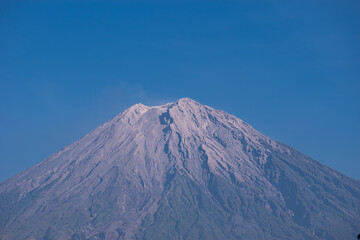 A stunning view of Mount Semeru’s summit captured under crystal blue skies, exposing the raw volcanic textures of Java’s most active and highest volcano.