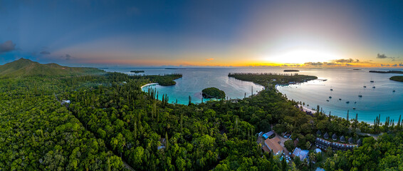 A beautiful twilight panorama of Kuto and Kanumera bays on the Isle of Pines. The lights of a luxury resort begin to glow as the sun sets over the tranquil turquoise water