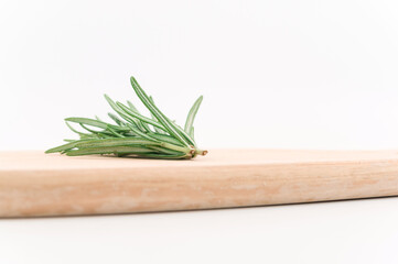 rametti di rosmarino fresco su un tagliere in legno vista macro ravvicinata, sfondo bianco