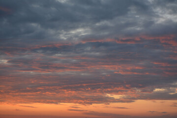 Fototapeta premium Orange sunset among gray clouds. Background