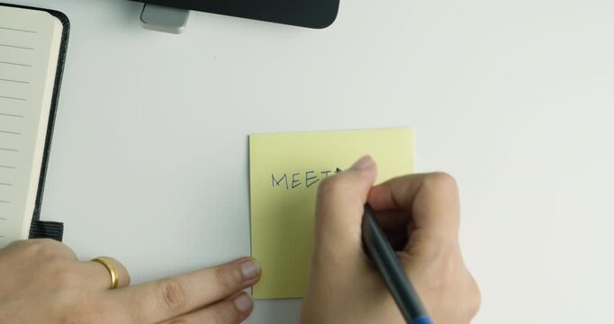 close up of a female hand with post it note reminder for meeting, Corporate work desk video, woman entrepreneur working, productivity and time management 