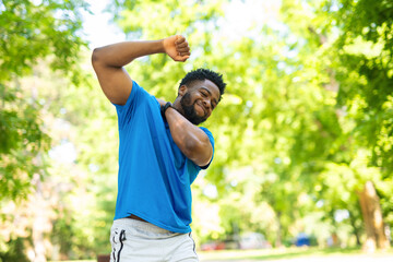 Obraz premium Young man feeling neck pain after outdoor workout. Athlete stretching and massaging sore muscles in park, concept of injury, recovery and health care. 