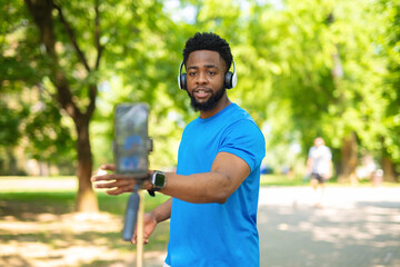 African american fitness vlogger recording video with smartphone outdoors.