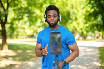 African american fitness vlogger recording video with smartphone outdoors.