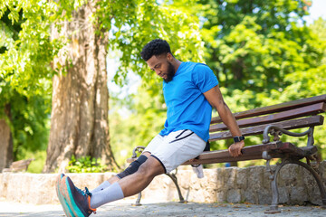 Athletic man doing triceps dips on a park bench. Focused male athlete exercising outdoors on a...