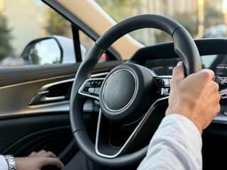 A young man driving a business car. A businessman's trip in sunny weather. The hand of a man holding the steering wheel of a car. 