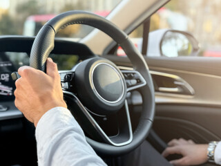 A young man driving a business car. A businessman's trip in sunny weather. The hand of a man holding the steering wheel of a car. 