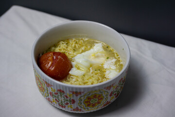 A Simple Homemade Meal of Instant Noodle Soup with Egg and Tomato in a Patterned Bowl