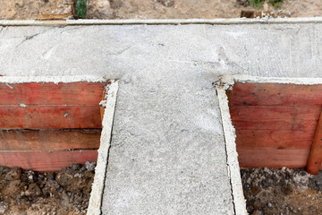 A concrete foundation is being formed between red wooden boards