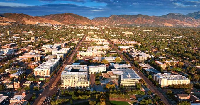 Urban landscape of Slat Lake City in the bright light of setting sun. Drone footage approaching the bare mountains range.