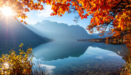 Serene mountain lake reflecting autumn foliage and sun rays on a clear day