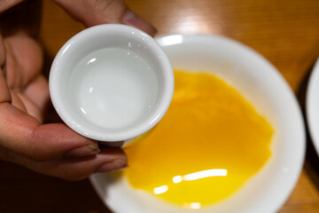 a small cup filled with erguotou on the pickled radish. Erguotou is a strong, clear distilled spirit (baijiu) from Beijing, China.