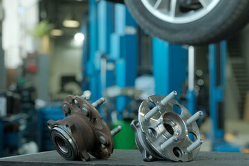 Car service. Spare parts. The suspension of the car.There are two rear wheel hubs on the mechanic's desk. One hub is defective, rusty. The other hub is new and ready for installation.