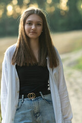 Obraz premium Portrait of a young beautiful long-haired girl in a black T-shirt outdoors.