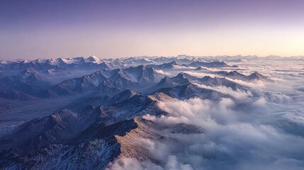 Aerial view of snow-capped mountains rising above a sea of clouds at dawn
