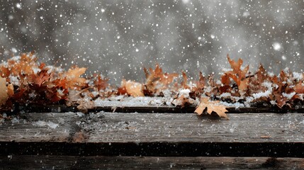 Snowfall beginning on top of a pile of leaves over wooden planks