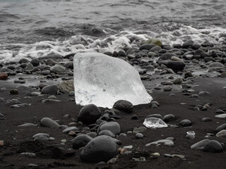 block of ice on black and volcanic sand