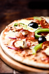 Pizza with chorizo ​​sausage, mozzarella cheese, green pepper and black olives. Rustic wooden background. Soft focus.	