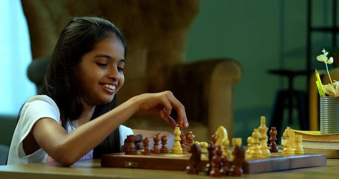 Indian small brother sister playing chess indoors at home, young siblings enjoying playful childhood activity in living room together, Asian kids bonding, family love, fun learning, strategy