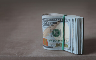 Money stack of folded hundred dollar banknotes on the table.