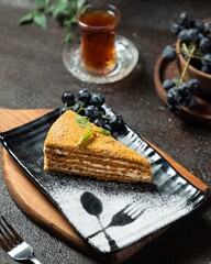 Delightful dessert featuring layered cake, fresh grapes, and tea on a rustic wooden table