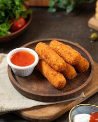 Crispy breaded sticks served with tangy sauce and fresh ingredients in a cozy kitchen setting
