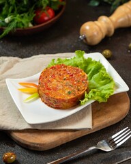 Delicious vegetable terrine served on a white plate with fresh lettuce and garnished with colorful vegetables